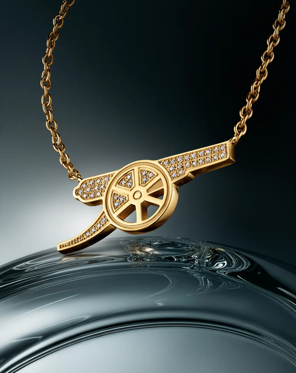 A gold openwork pendant necklace on a rippled dark surface · Jewellery photography, TimeLäB Studio Barcelona
