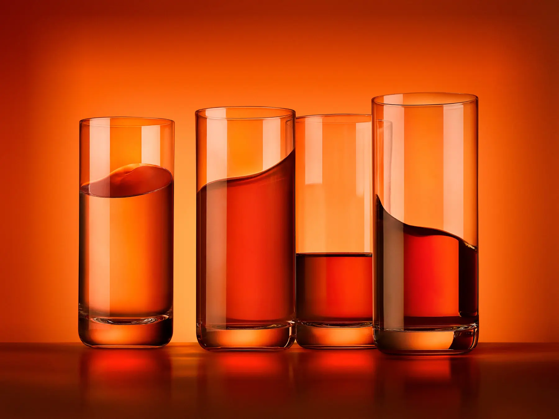 Four tumblers of an orange drink on an orange backdrop · Product photography, TimeLäB Studio Barcelona
