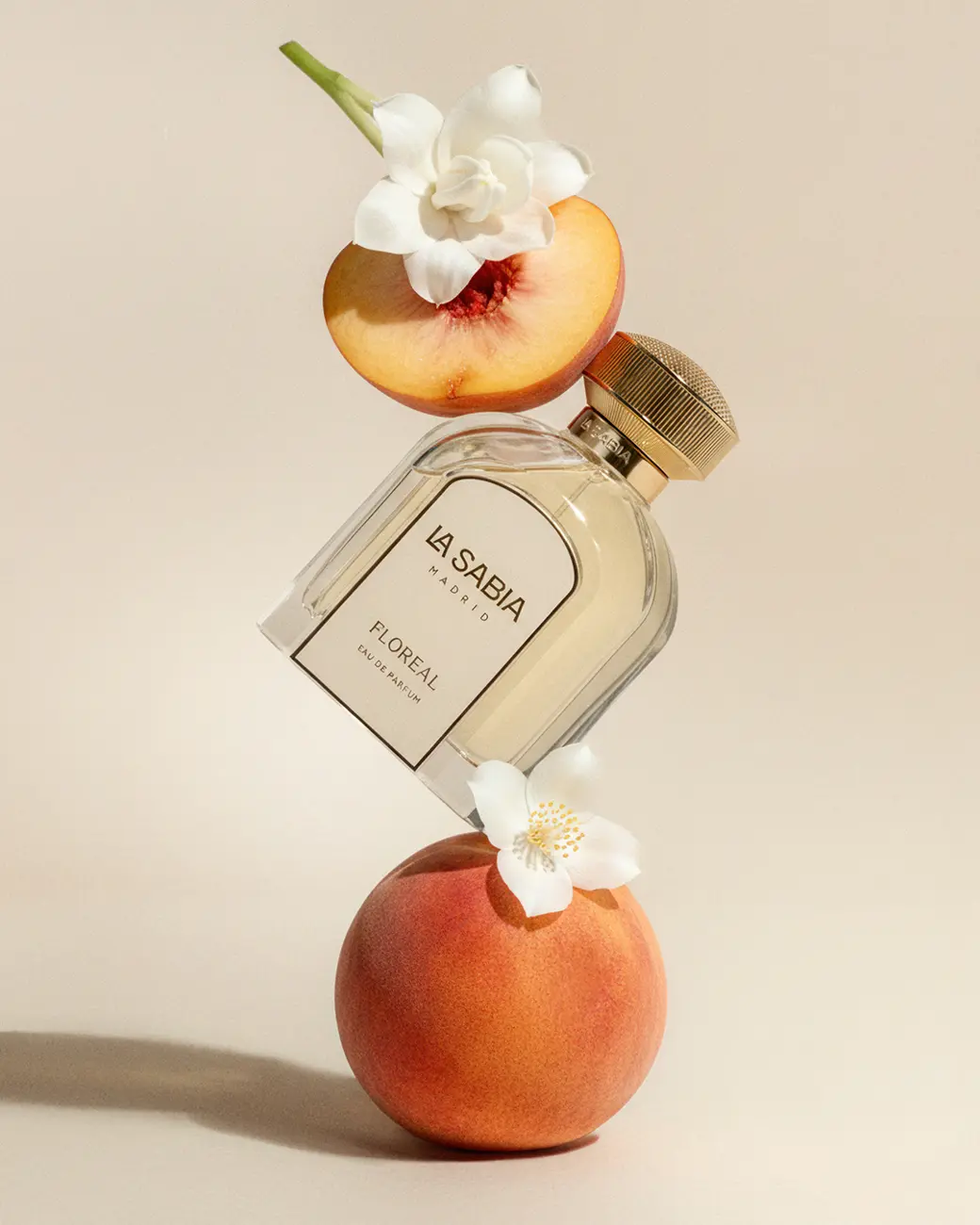 A bottle tilted over a peach, with jasmine · TimeLäB Studio