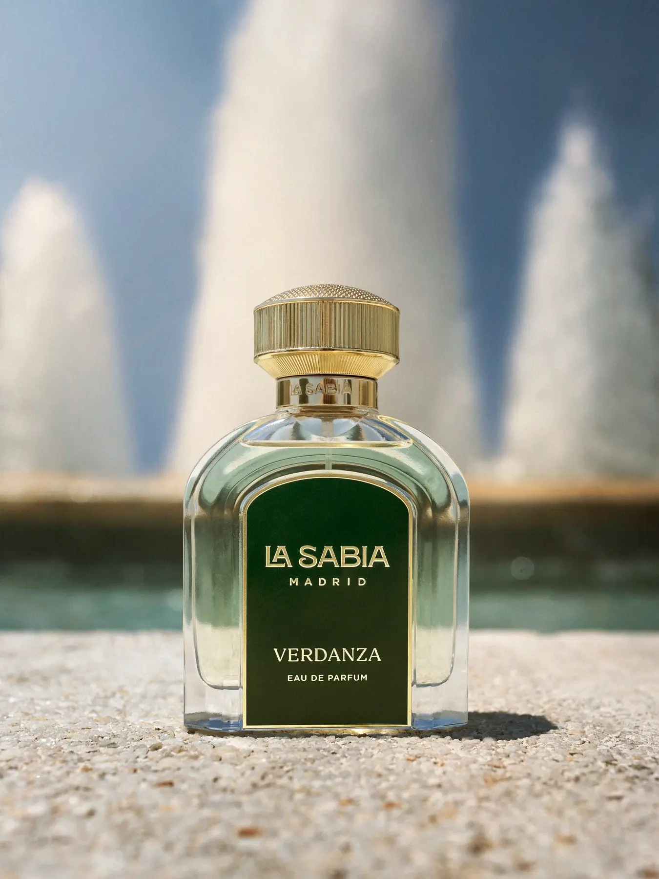 A fragrance on sand, with fountains rising behind · TimeLäB Studio